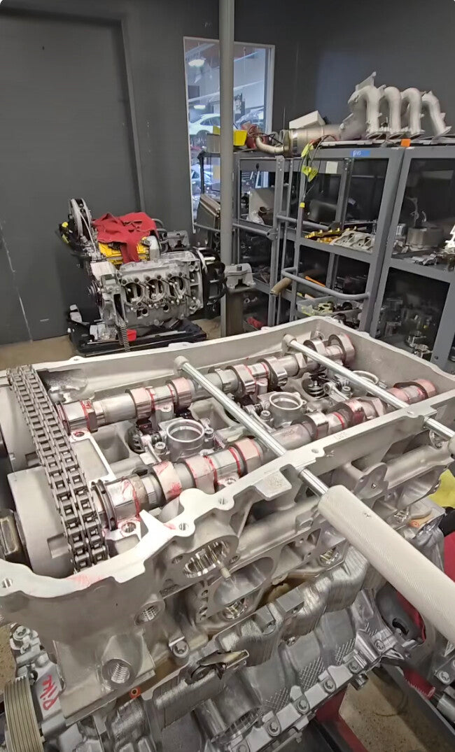GT3 engine on a stand with cam covers off and the chopstick tools in place holding the cams and followers down