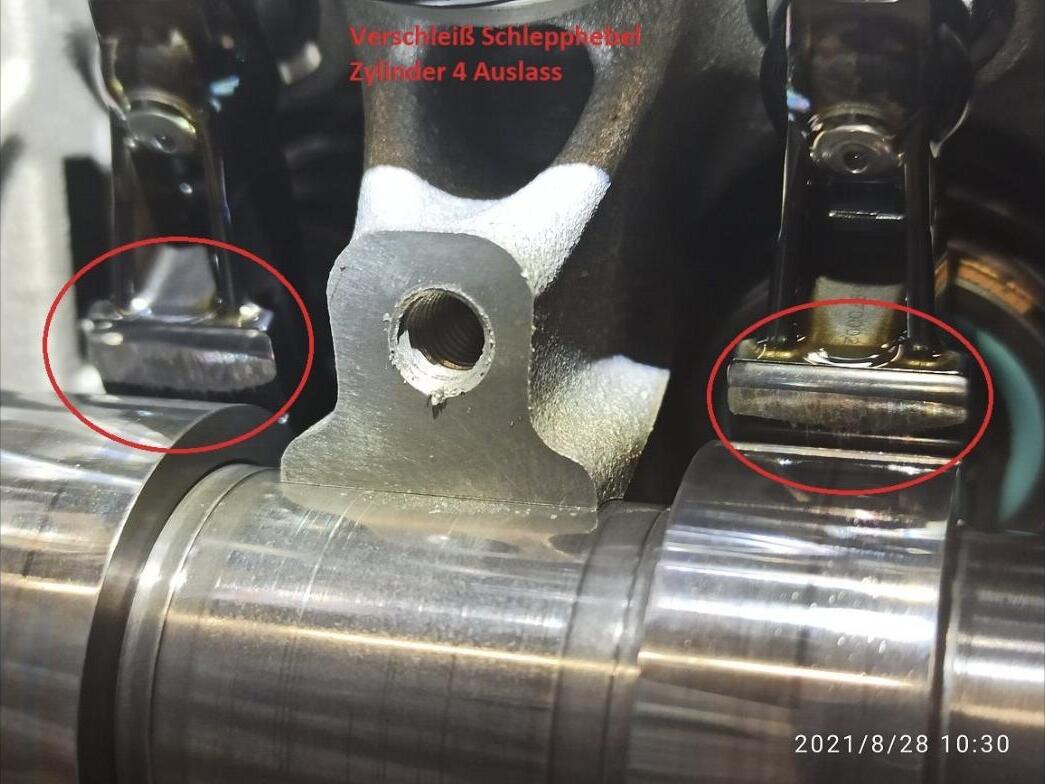 Worn finger followers on cylinder 4 exhaust with DLC coating polished through, circled in red