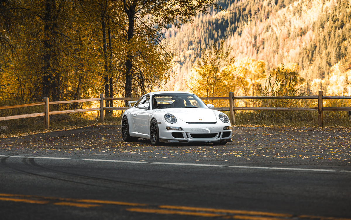 A white Porsche 997 GT3 on an autumn mountain road
